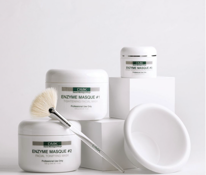 DMK Enzyme Masque range on White backhround along with a brush and white bowl for mixing