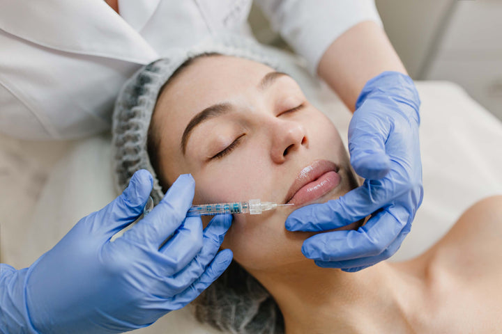 A medical professional in white overall injecting on lips of lady, lying down with eyes closed